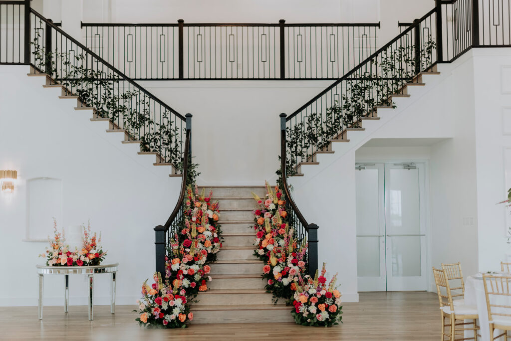 Grand staircase decorated with florals and greenery at wedding venue