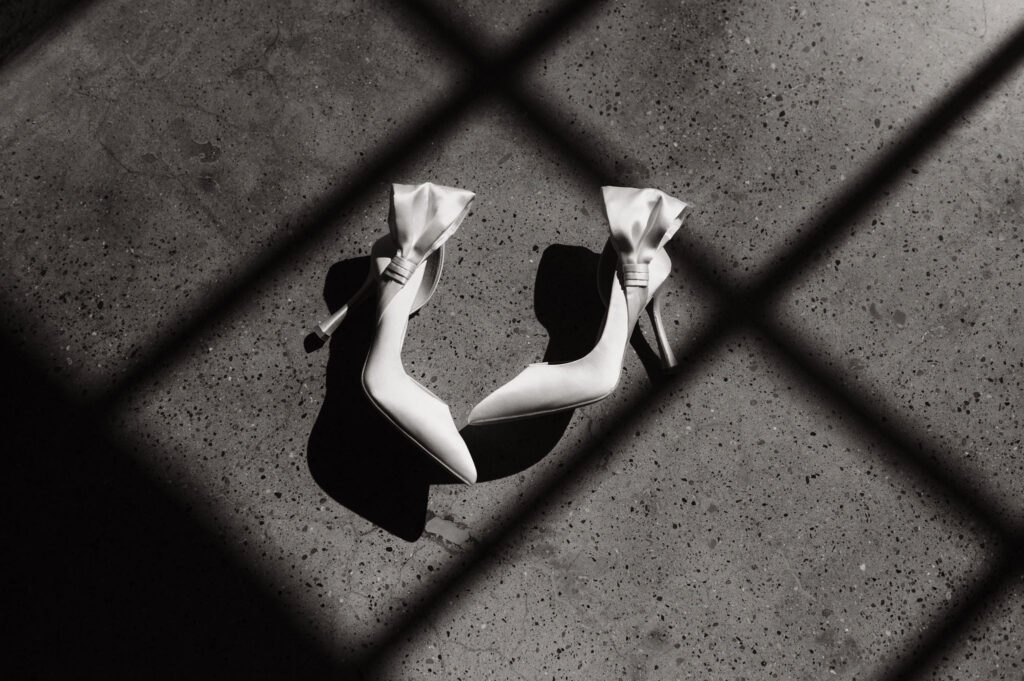 Black and white photo of bride’s shoes photographed through window shadows