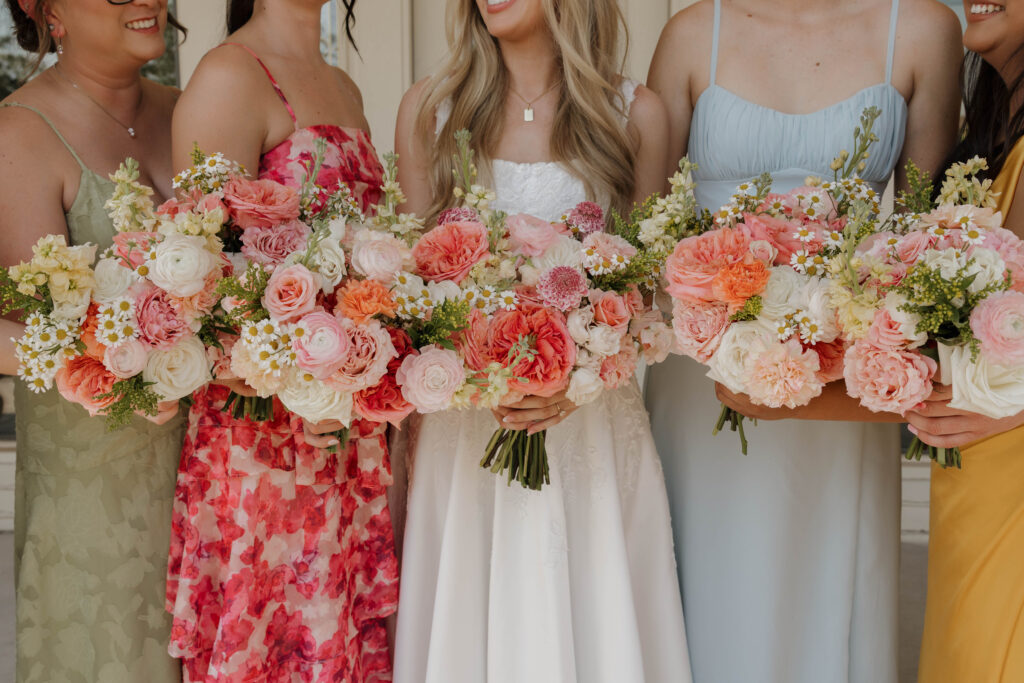 Bridesmaids holding colorful floral bouquets in coordinated dresses