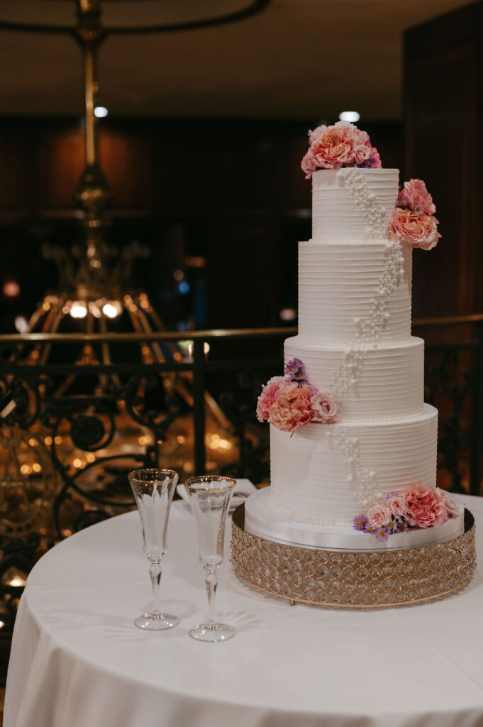 White tiered wedding cake with pink flowers at The Adolphus in Dallas