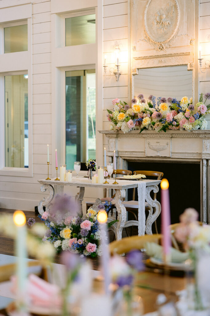 Wedding reception with fireplace with large floral design and colorful candles and flowers on the tables