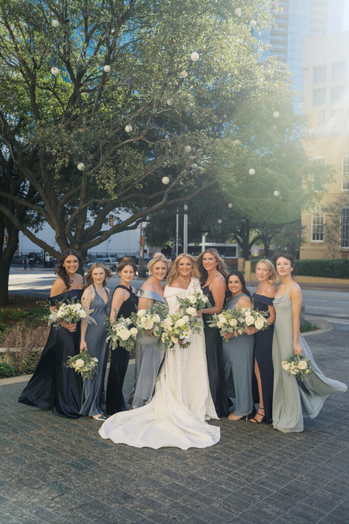 Bride posing with bridesmaids in blue dresses with white bouquets for a winter wedding in Dallas