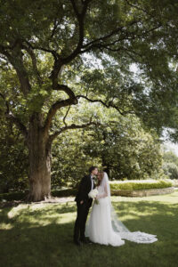 Bride and groom kissing under a tree at Dallas Arboretum