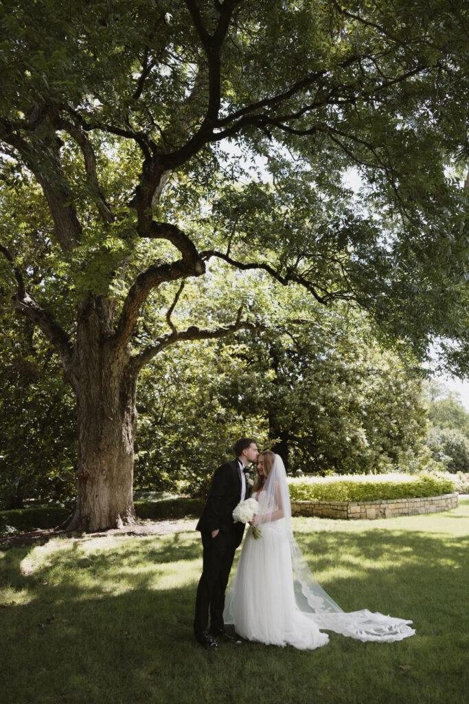 Bride and groom kissing under a tree at Dallas Arboretum