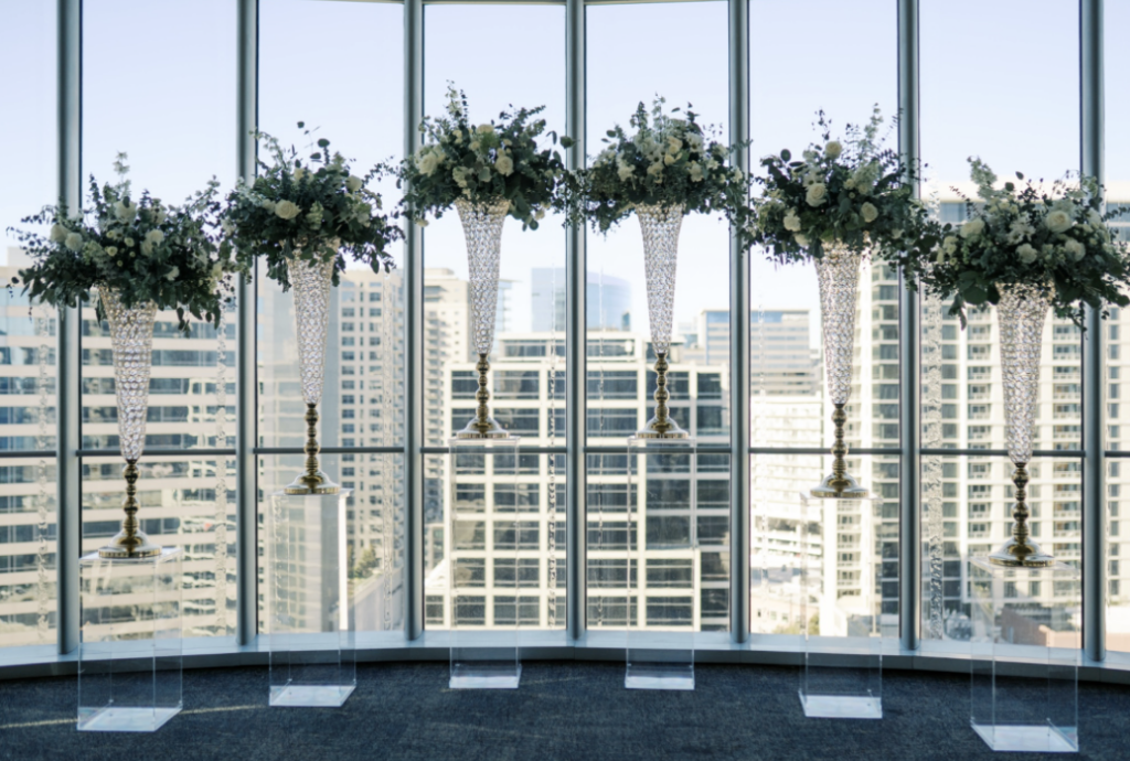 Large vases of white flowers against a window at wedding reception at the Dallas Petroleum Club