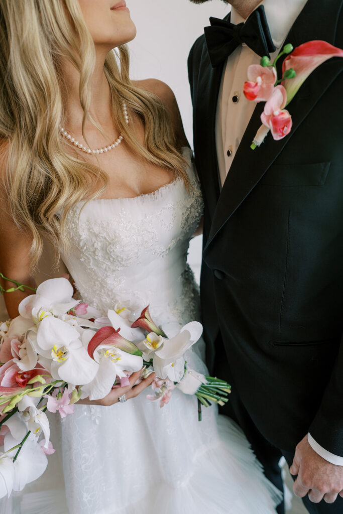Closeup of bride and groom looking at each other with bride holding orchid bouquet and groom wearing orchid boutonniere