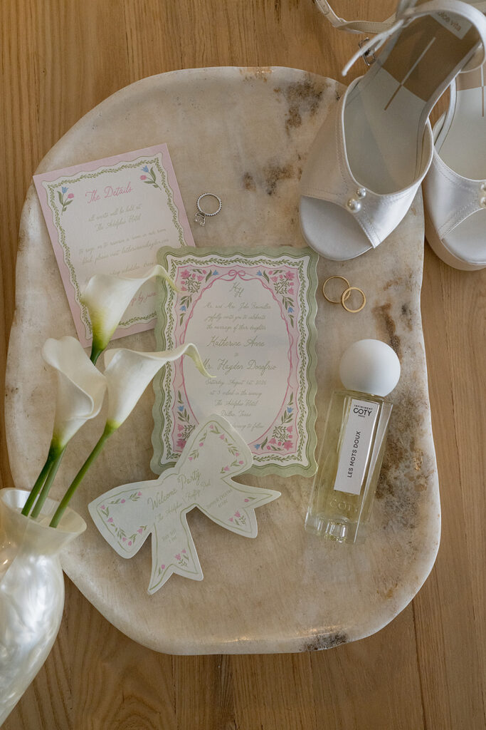 Flatlay of wedding details and invitations with green and pink floral designs