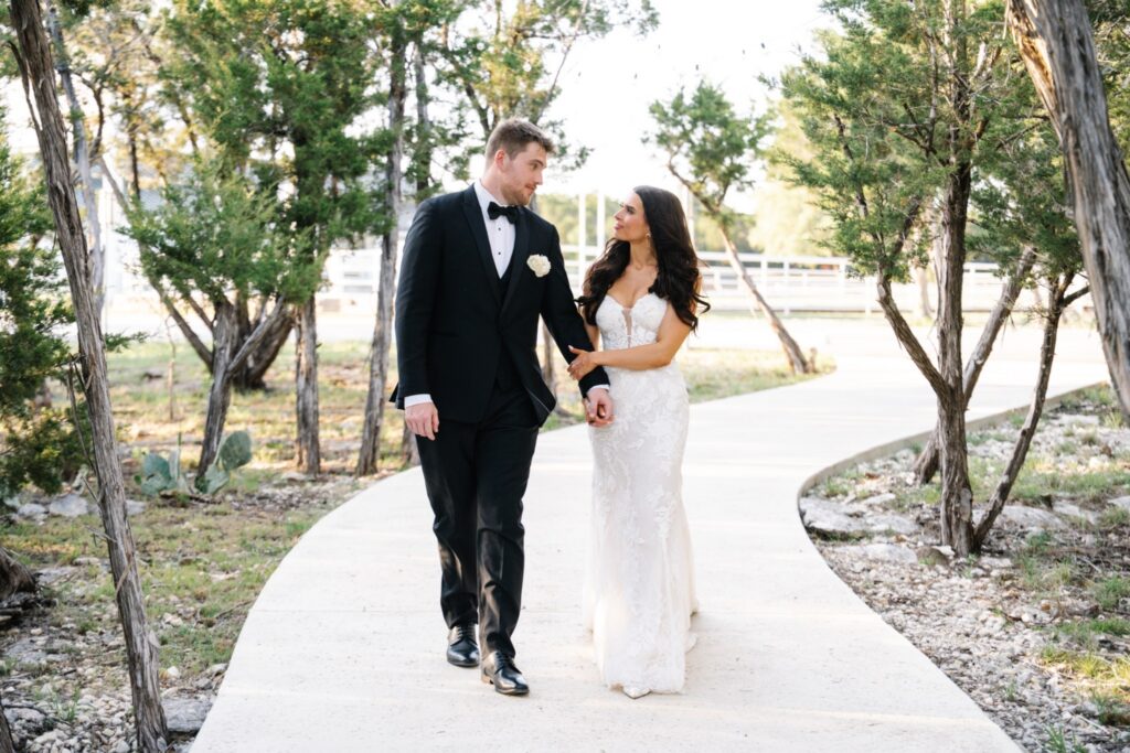 Bride and groom walking down a pathway under trees